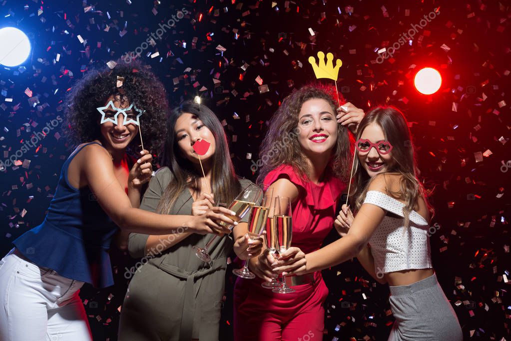 Gruppe von Freunden mit bunten Accessoires vor der Fotobox